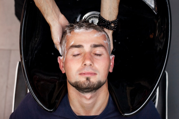 Hände waschen die Haare eines Mannes im Schönheitssalon