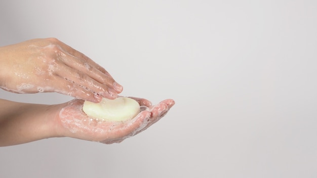Hände waschen Geste mit Seifenstück und Schaumblase auf weißem Hintergrund.