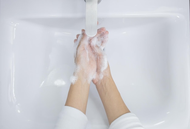 Hände waschen mit Seife unter dem Wasserhahn mit Wasser