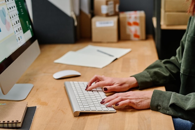 Hände weiblicher Freiwilliger, die am Schreibtisch auf der Computertastatur tippen