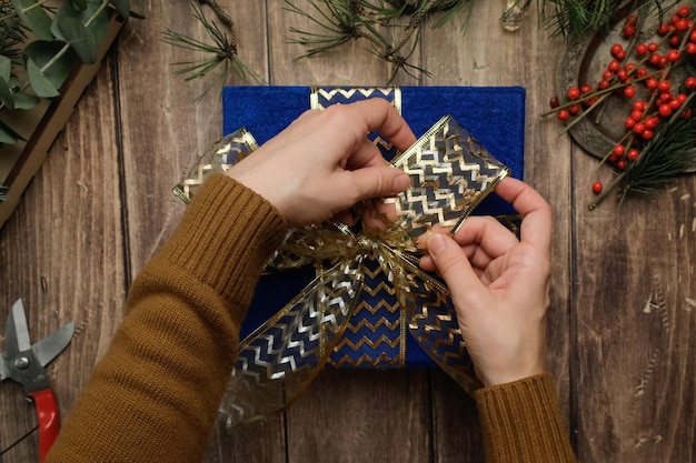 Hände wickeln Weihnachtsgeschenk mit Schleife dekorieren