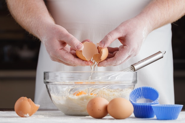 Hände, Zutaten und Geräte für die Zubereitung von Cupcakes. Hausgebäck. Food-Konzept. Mehl, Eier, Butter, Gebäck mischen