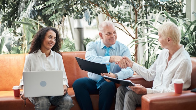 Händedruck von Geschäftspartnern, die im Büro auf der Couch sitzen