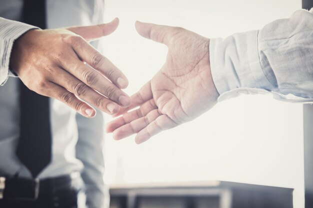 Händeschütteln mit zwei Geschäftsmännern, nachdem gutes Abkommen des Handelsvertrages besprochen worden ist