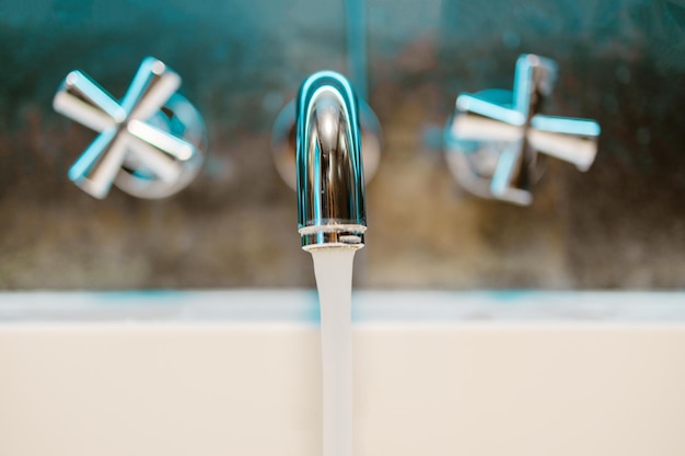 Händewaschen im Waschbecken zu Hause. Schließen Sie den offenen Chrom-Metall-Silber-Hahn mit weißer Keramikbadewanne im luxuriösen Badezimmerwandhintergrund