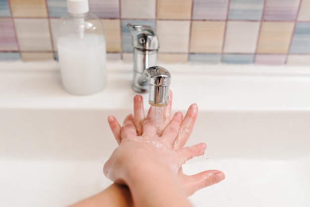 Händewaschen und Hygiene. Coronavirus, Prävention von Grippeerkrankungen. Waschen Sie die Hände der Frau mit antibakterieller Seife, warmem Wasser und reiben Sie die Nägel und Finger im Waschbecken.