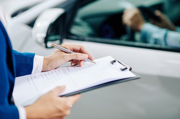 Händler-Manager, der Kundeninformationen ausfüllt, wenn der Kunde das Auto vor dem Kauf testet