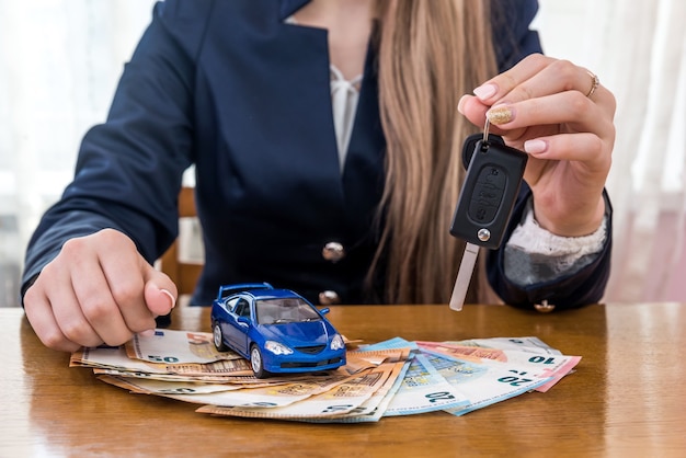 Händler mit Schlüsseln von Auto, Spielzeugauto und Euro-Geld