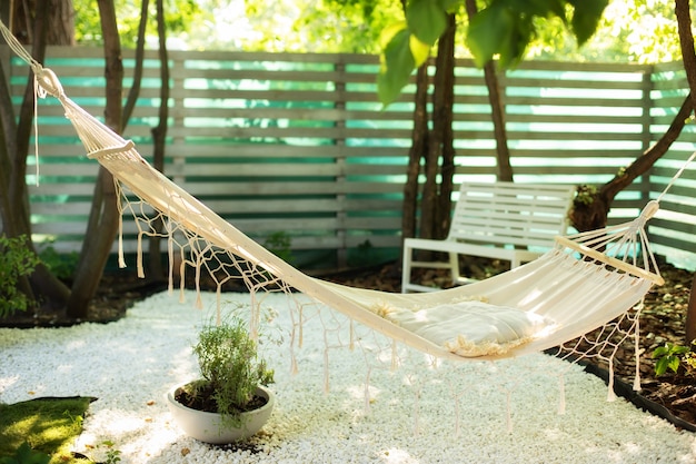 Hängematte hängend im Garten Gemütlicher Außengarten Hängematte im Boho-Stil, die am Baum hängt