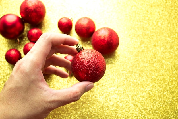 Hängen Sie einen roten Dekor-Glitzerball auf goldenem Hintergrund auf