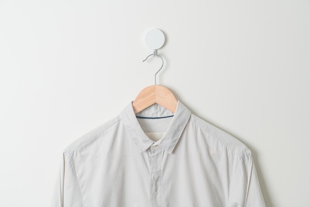 Foto hängendes beiges hemd mit holzbügel an der wand