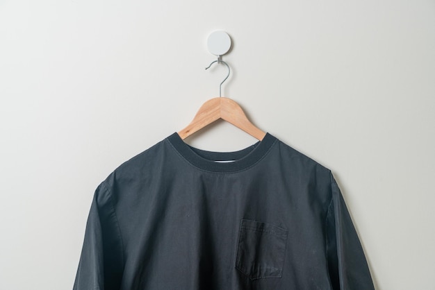 Foto hängendes schwarzes hemd mit holzbügel an der wand