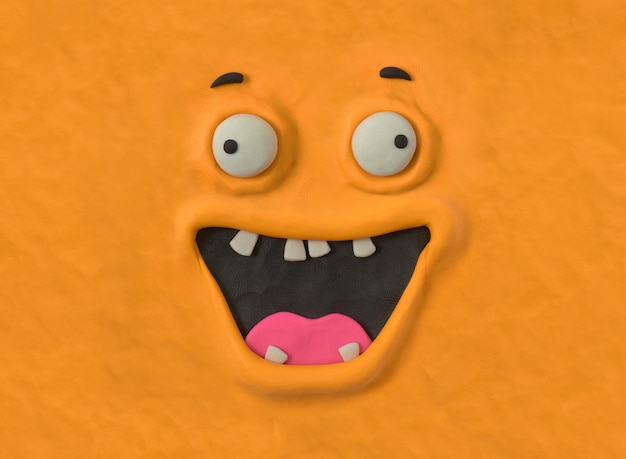 Hässliche Monsterkreatur von Hand aus orangefarbenem Plastilin Hässliches Monstergesicht emotionaler Ausdruck