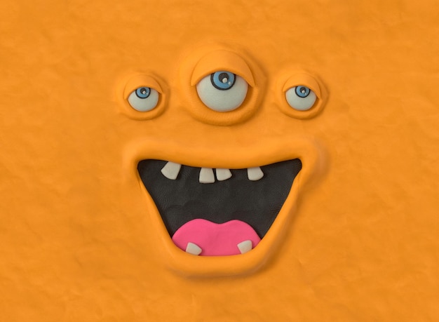 Hässliche Monsterkreatur von Hand aus orangefarbenem Plastilin Hässliches Monstergesicht emotionaler Ausdruck