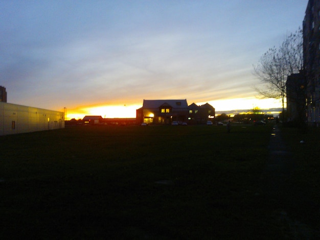 Foto häuser auf dem feld gegen den bewölkten himmel bei sonnenuntergang