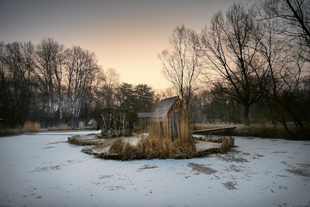 Häuser inmitten eines gefrorenen Sees im Wald bei Sonnenuntergang