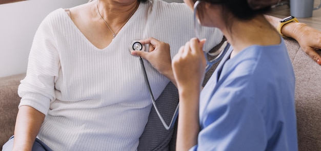 Häuslicher Pflegedienst und ältere Menschen Kardiologie Gesundheitswesen Nahaufnahme einer jungen hispanischen Ärztin, die den Herzschlag eines reifen kaukasischen Mannes mit einem Stethoskop während des Besuchs überprüft