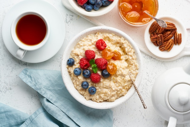 Haferbrei mit Blaubeeren, Himbeeren, Marmelade und Nüssen, Draufsicht. Frühstück mit Beeren