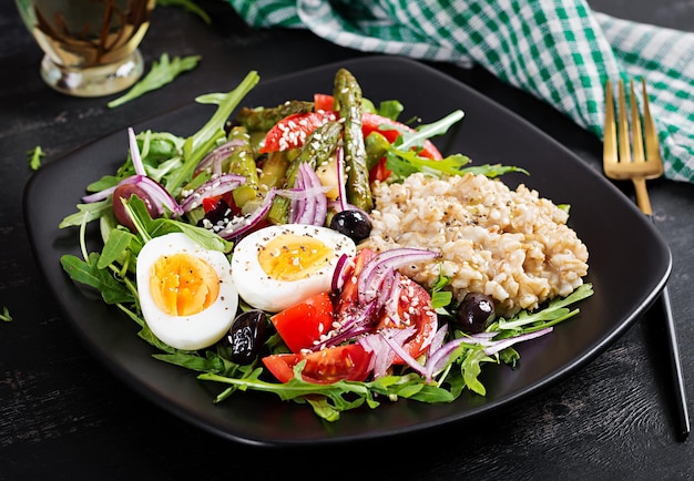 Haferbrei zum Frühstück mit gekochtem Ei Kirschtomaten Spargel und Rucola Gesundes, ausgewogenes Essen