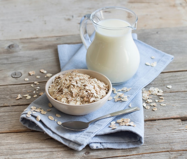 Haferflocken in einer Schüssel und Milch auf einem Holztisch