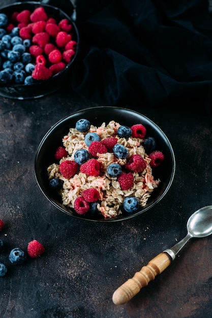 Haferflocken mit Himbeeren und Blaubeeren in einem schwarzen Teller