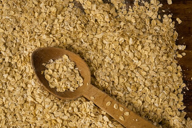 Haferflocken und Holzlöffel auf einem Holztisch.