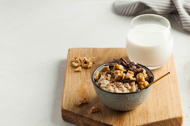 Haferflockenbrei mit Nussschokolade in einer grauen Schüssel ein Glas Milchfrühstück gesunder Foodcopy Space...