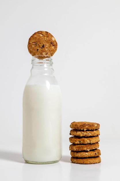 Foto haferflockenkekse neben einer milchflasche mit einem keks im mund und einem hellen hintergrund