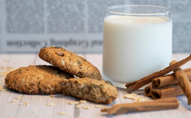 Foto haferkekse, milch und zimt auf holzhintergrund