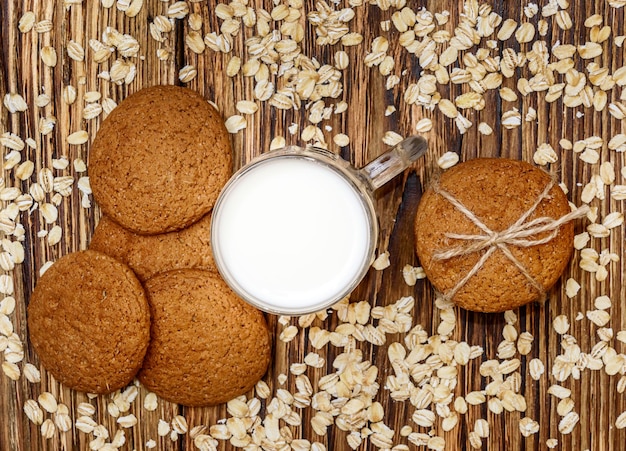 Haferkekse mit Glas Milch und Haferflocken auf Holzhintergrund