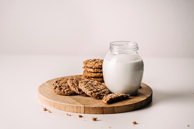 Haferkekse mit Milch auf Tablett auf rustikalem Holztisch Weißer Hintergrund