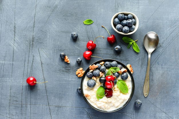 Hafermehl-Getreide-Brei mit frischen Beeren in der schwarzen Schüssel. Gesunde Ernährung Frühstück