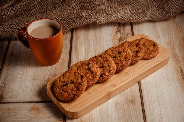 Hafermehlplätzchen auf einem hölzernen Stand und einem Kaffee mit Milch