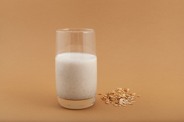 Hafermilch im Glas auf beigem Hintergrund Proteinshake oder Mehrkorn-Smoothie