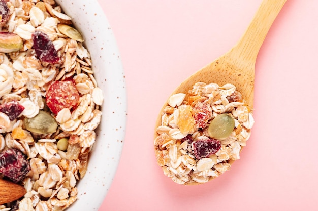 Hafermüsli mit getrockneten Beeren und Samen der Nüsse auf einer rosa Hintergrundnahaufnahme