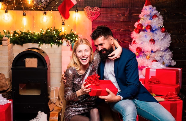 Haga una cara graciosa pareja de moda sobre las luces del árbol de Navidad expresión de fondo y concepto de la gente