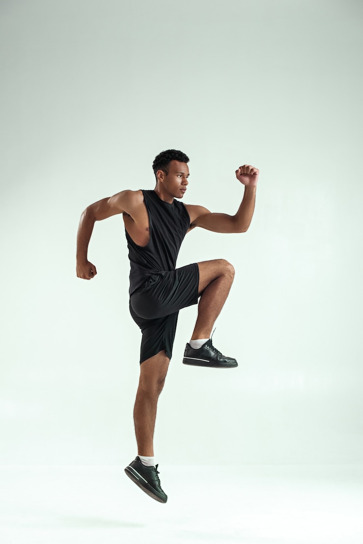Foto hágalo de cuerpo entero de joven africano con cuerpo musculoso en ropa deportiva saltando