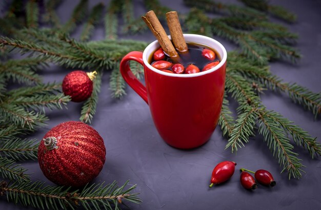 Hagebuttentee mit Zimt-Fichtenzweigen und Weihnachtskugeln