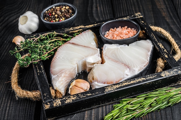 Hai rohe Fischsteaks in einem Holztablett mit Kräutern