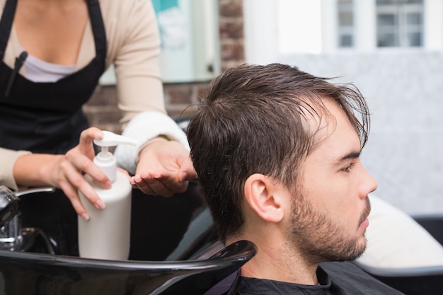 Hair stylist putting conditioner in mans hair