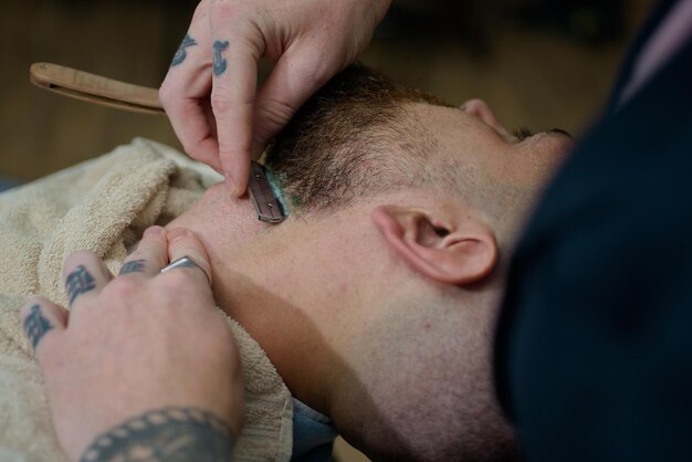 Hair Stylist und Barber Friseure arbeiten für einen gutaussehenden Mann im Friseursalon. Friseurscheren und Rasiermesser