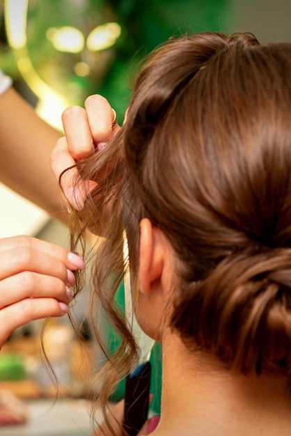 Hairstyling-Braut Ein weiblicher Friseur macht Styling-Haare für die schöne junge kaukasische Frau in einem Schönheitssalon