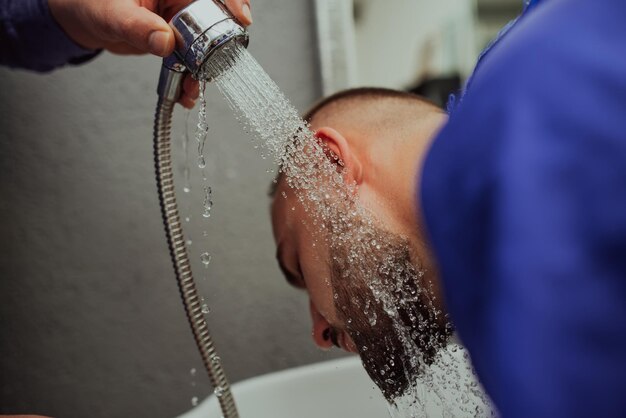 Hairstylist, der die Bären des Kunden 39 in einem Friseursalon wäscht. Selektiver Fokus. Foto in hoher Qualität