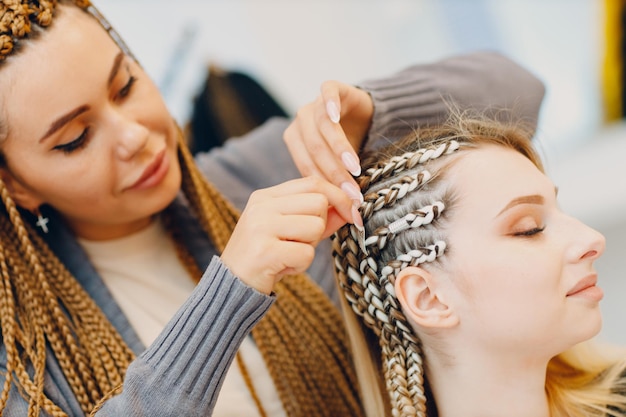 Hairstylist geflochtene Afro-Zöpfe Zöpfe Haare der Kundin im Friseursalon