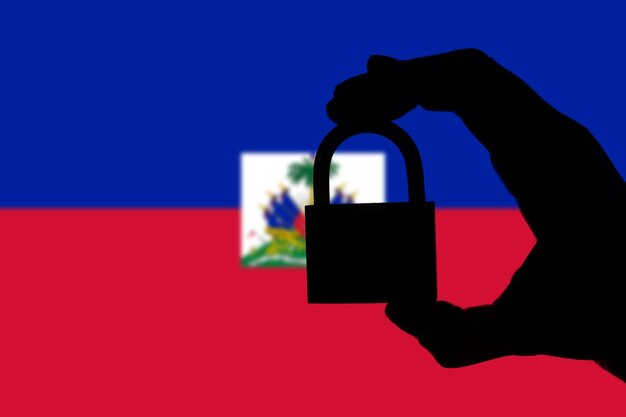 Haiti-Sicherheit Silhouette einer Hand, die ein Vorhängeschloss über der Nationalflagge hält