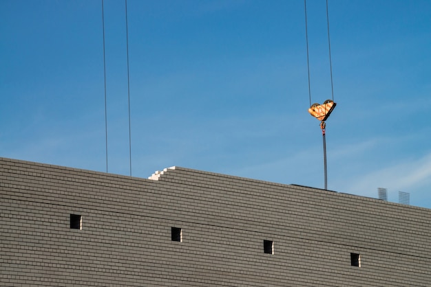 Haken des Turmkrans über unvollendetem Gebäude auf der Baustelle