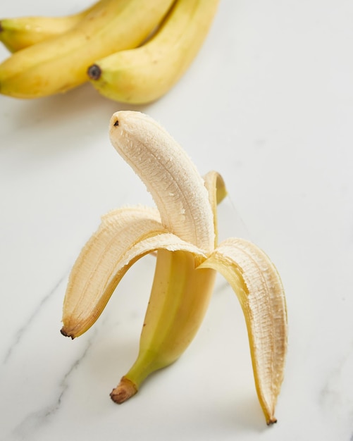 Halb abgezogene reife Banane auf weißem Hintergrund