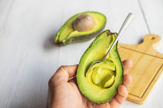 Halb geschnittene Avocado auf einem weißen Holztisch