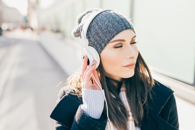 Halbe Länge der hörenden Musik der jungen schönen kaukasischen Frau