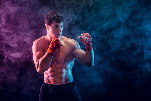 Halbe Länge des hemdlosen Boxerkämpfers, der sich auf den Kampf auf Rauchhintergrund vorbereitet Sportkonzept